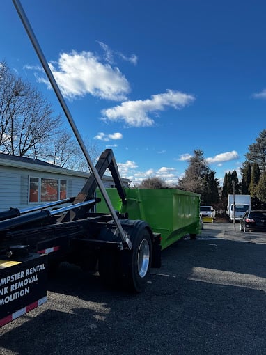 Green dumpster on truck parked in residential neighborhood on sunny day
