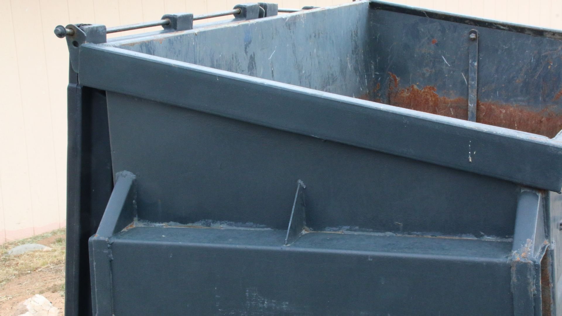 Large blue-gray metal dumpster with rust marks outdoors
