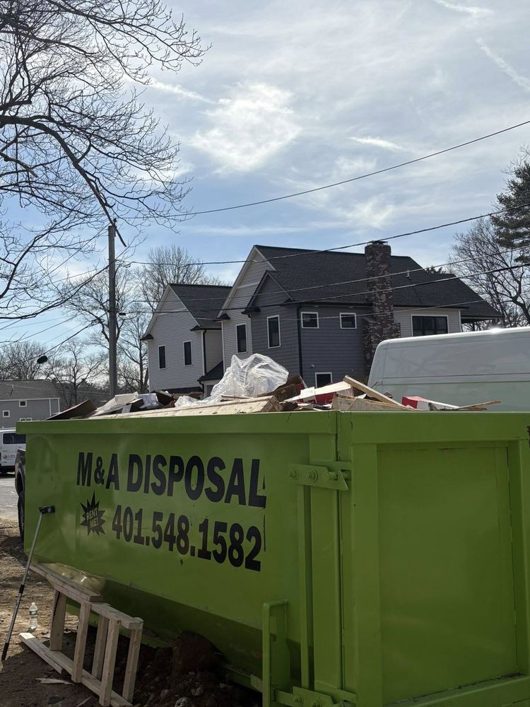 Green disposal dumpster in residential area with construction debris