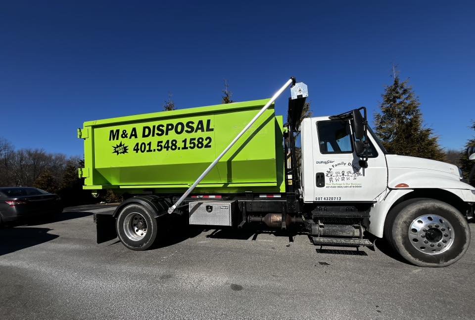 Bright green M&A Disposal truck parked in a lot on a clear day